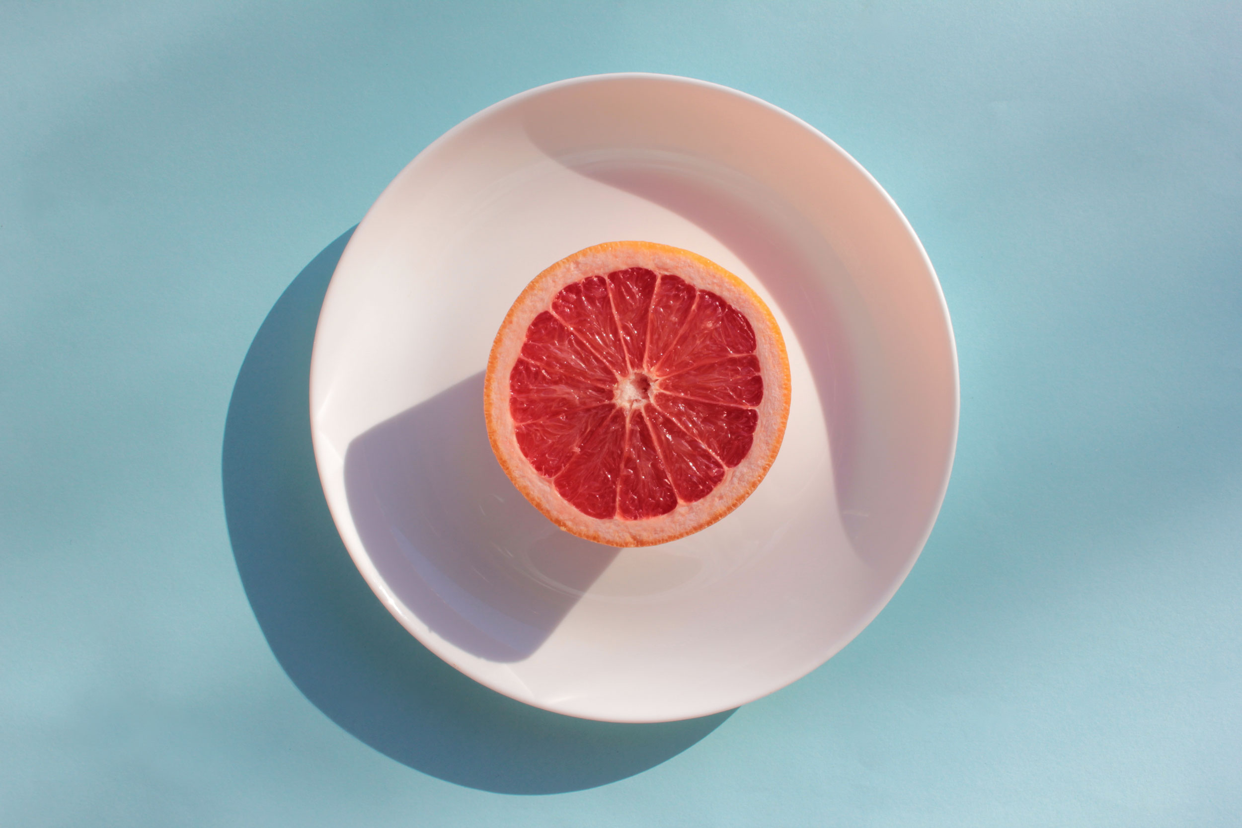 half-of-ripe-grapefruit-on-white-plate-on-light-bl-2022-03-06-04-17-14-utc